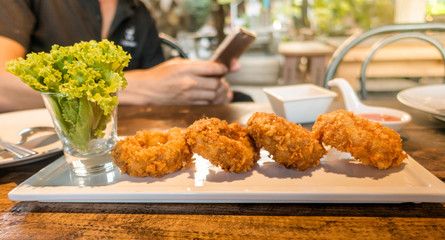 Thai fried fish patty with man using smart phone