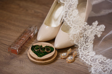 Wedding accessories: bridal shoes, perfume bottle, veil, jewelry and wedding ring in box with moss