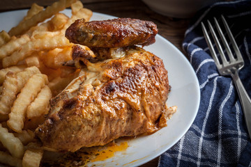 Roasted chicken with french fries on a plate.