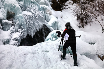 Landscape photographer at frozen waterfall