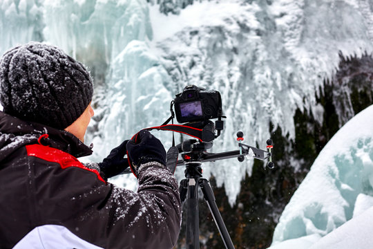 Landscape photographer at frozen waterfall