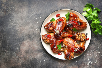 Spicy chicken wings with teriyaki sauce and sesame seeds on a vi