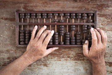 old abacus and hand on wooden background