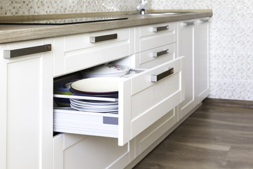 Opened kitchen drawer with plates inside, a smart solution for kitchen storage and organizing. 