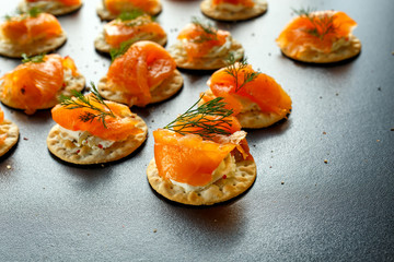 Smoked Salmon and soft chees canapes appetizers with chives on stone table