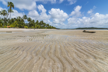 Fototapeta na wymiar Sand wave-shaped and old raft in a tropical beach