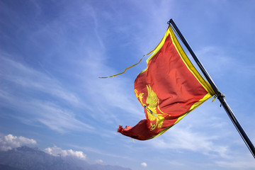 Old Montenegrin flag fluttering in the wind on the ship. Burnt a