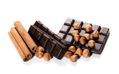 chocolate bars with cinnamon sticks and pile hazelnuts isolated on white background