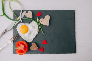 valentine day.romantic breakfast. fried egg, bread and vegetables on wooden tray