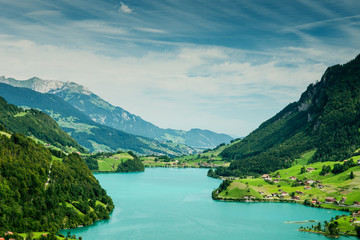 Naklejka na ściany i meble Aerial view of lake with mountains and green meadows in Switzerland 