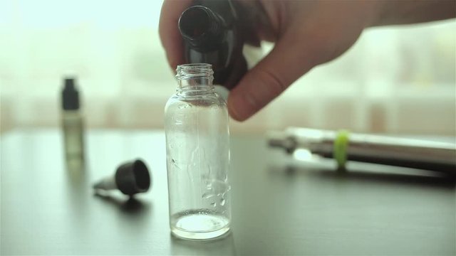 Man's hand pours a liquid for e-cigarette in the bottle. Electronic cigarette.