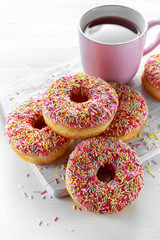 Iced doughnut rings with rainbow sparkl strands and cup of coffee, tea