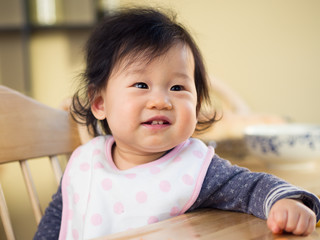 Naklejka premium Baby girl sitting on high chair waiting for food