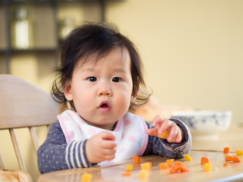 baby girl eating  vegetable first time at home