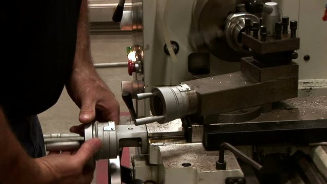 A metal working using a metal lathe on a piece of stainless steel tubing.
