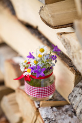 Beautiful summer wild flowers in a nice glass jar on a wooden background. Summer bouquet. Bunch of flowers. Summer time. Present.