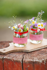 Beautiful summer wild flowers in a nice glass jar on a wooden background. Summer bouquet. Bunch of flowers. Summer time. Present.