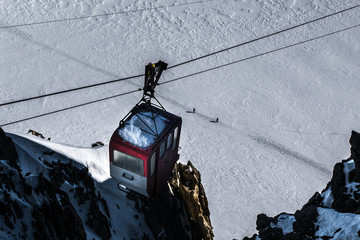 Decommisioned cable car hanging from cables over skiers traversi