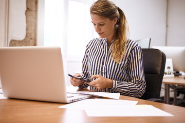 Business woman making calculations on phone