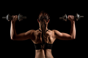 Fototapeta na wymiar Atractive fit woman works out with dumbbells as a fitness concep