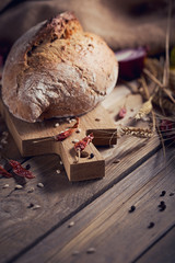 Fresh multigrain crusty bread and wheat ears on a rustic wooden