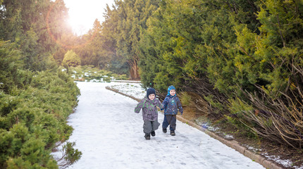 Two little kids boys, friends holding hands and hugging. Adorable siblings in bright colorful clothes. Happy children outdoors, winter or autumn