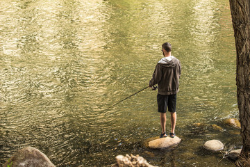 Man Fishing Along River Bank