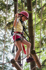 Kindesentwicklung in Balance - Mädchen im Kletterpark balanciert geschickt über schwebende Balken