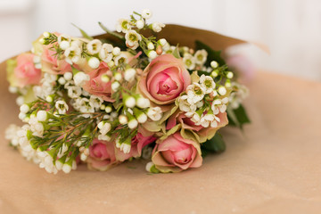 Beautiful bouquet of pink roses and daisies in the craft paper. Flowers. Present for birthday. Stylish flower bunch ready for wrapping.