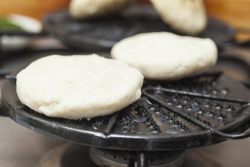Colombian arepas being roasted on a round grill