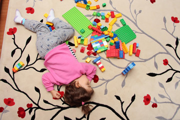 a child sleeping on carpet with her toys