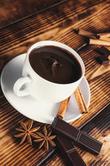 cup of hot chocolate, cinnamon sticks, nuts and chocolate on woo