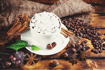 cup of hot chocolate, cinnamon sticks, nuts and chocolate on woo