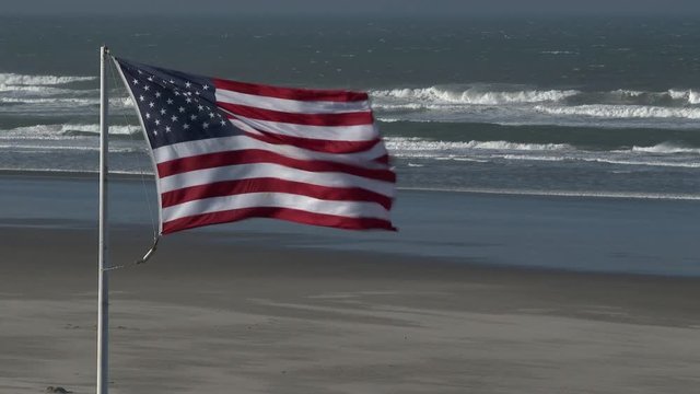 American Flag blowing as strong winds reach the beach of the Pacific Coast in Seaside, Oregon.