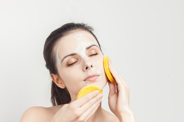 woman with closed eyes rubs her face with a sponge