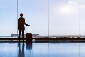 Traveler businessman in airport lounge waiting for flight, standing