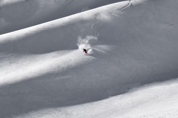 Solo lone skier putting down fresh first tracks on mountain ridg