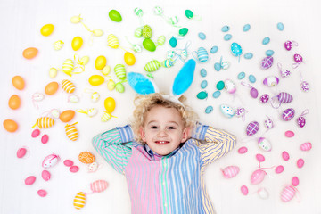Child on Easter egg hunt. Pastel rainbow eggs.