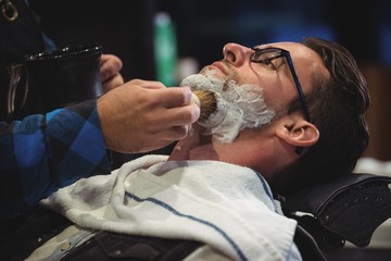 Mid section of barber applying cream on clients beard