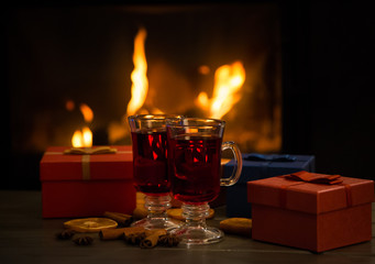 Hot wine in glass in front of fireplace with Christmas gifts
