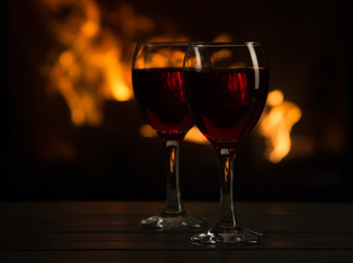 Two glasses of red wine in front of the fireplace.