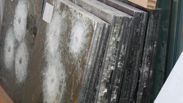 a Specialist Counts Sheets of Bulletproof Mirror Glass, Made of Several Layers, With Round Cracks and Fractures From the Bullets, Being Shot by a Steadicam Camera