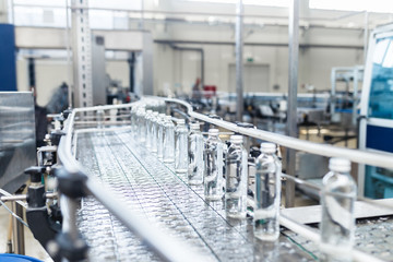 Fototapeta na wymiar Water factory - Water bottling line for processing and bottling pure spring water into small glass bottles. Selective focus.