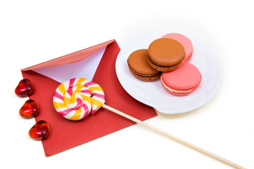 Open red envelope, lollipops and macarons on the white background.