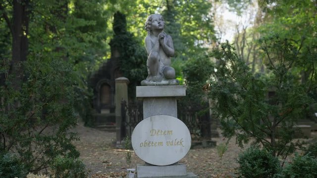 A shot that rotates around a statue of a child pleading for their life in Olsany Cemetery in Prague.  The inscription reads: "Children Victims of War". 4k.