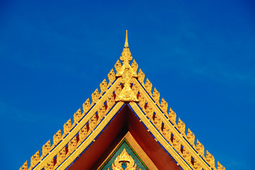 Gold color roof of buddhist temple with blue sky background.