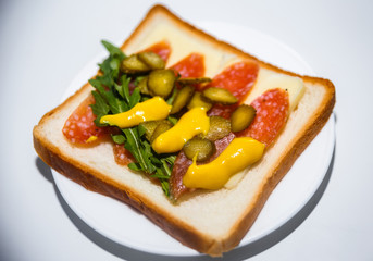 Sandwich with sausage salami, cheese suluguni, mustard, arugula and cucumber for breakfast