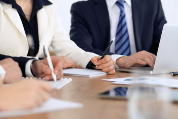 Group of business people at meeting, close up of human hands in work with pen and papers