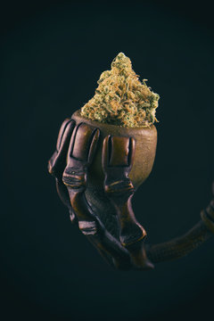 Cannabis bud on rustic pipe isolated over black background - med