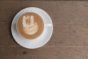 White cup of coffee on wooden table in the coffee shop.